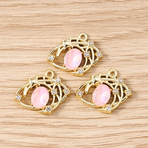 Vue macro de trois pendentifs étoile dorés avec pierres roses sur fond en bois clair