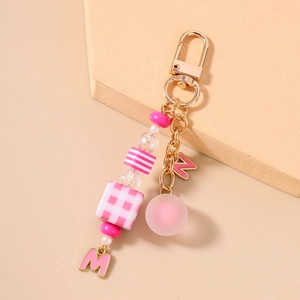 Detailed view of pink beaded keychain with golden letter M charms and checkered beads