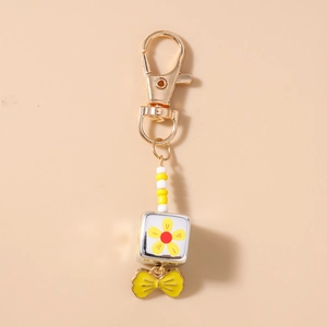 Detail of beaded keychain with yellow flower square bead and elegant bow charm