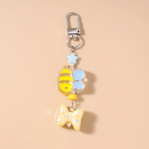 Detailed view of beaded bee keychain with acrylic bow and star charms on beige background