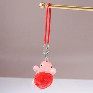 Detailed view of a pink resin turtle charm with red shell and silver metallic clip