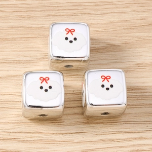 Macro shot of silver cube beads with white puppy charms and red bows for DIY jewelry