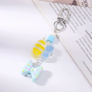 Detail view of cartoon bee and colorful bow pendants on a silver metal keychain