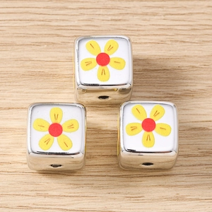 Macro view of silver square metal beads with floral pattern for DIY jewelry making