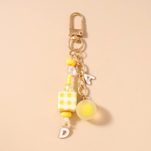 Close-up of yellow beaded keychain featuring golden D-clasp and letter pendants