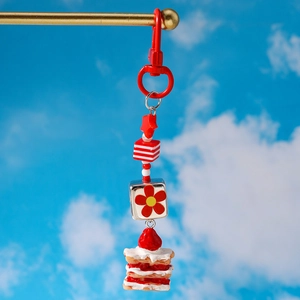 Détail d'un porte-clés gâteau à la fraise avec perles rouges sur fond de ciel bleu