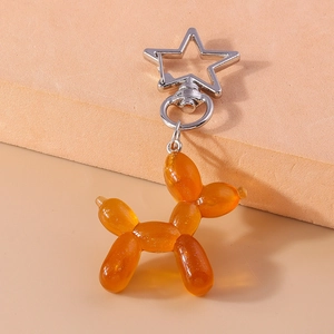 Dettaglio portachiavi a forma di cane palloncino in resina arancione con gancio a stella in metallo