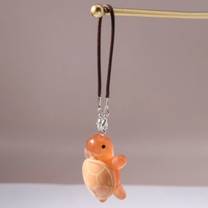 Detailed view of the translucent orange turtle charm with fine engraved shell texture