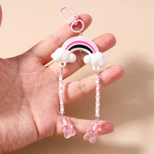 Detail of cute rainbow cloud keychain with pink beads and bear pendants held in hand