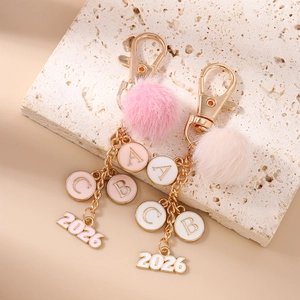 Portachiavi alla moda con pompon in ecopelliccia, numero 2026 e ciondoli con lettere oro