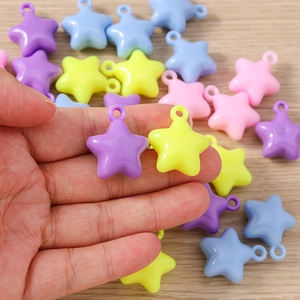 Colorful macaron star-shaped charms for jewelry making held in hand over wood
