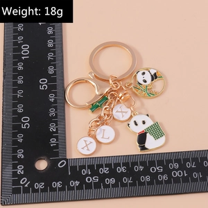 Golden panda keychain with bamboo charm and letter tags displayed on a black ruler scale