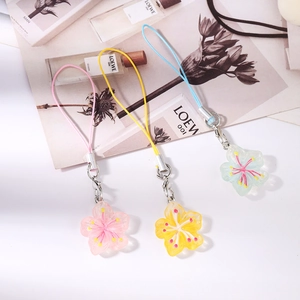 Détail de breloques de téléphone fleurs en résine rose, jaune et bleue avec fermoir