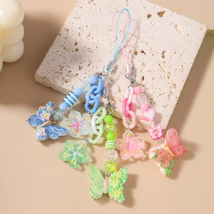 Bunte Perlen-Handykette mit Schmetterlings- und Blumenanhänger auf hellem Natursteingrund