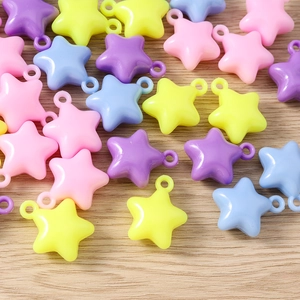 Macro view of colorful macaron star charms with top hooks on a light wood background