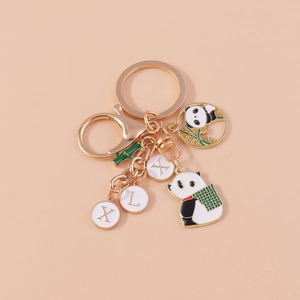 Panda keychain with bamboo charm and golden letter charms on a light apricot background