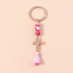 Detail of pink marble beads and golden cross pendant with sparkling rhinestones and silk tassel