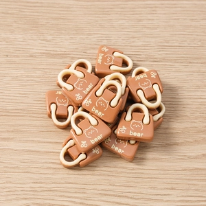 Makro-Detail von Mini-Taschenanhängern aus braunem Harz mit Bärendruck auf Holzgrund
