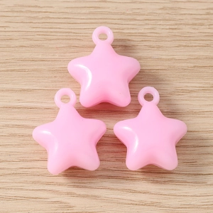 Close-up of three pink star charms with hooks on a natural wood surface for DIY jewelry