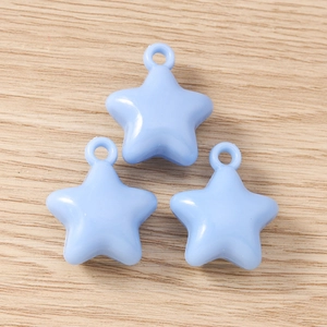 Macro shot of three light blue star pendants for DIY jewelry making on wood texture