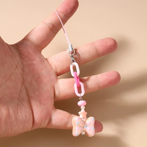 Close-up of pink resin butterfly charm with bead chain and star pendant on hand