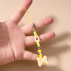Detail of yellow and white resin phone charm with chunky chain links and bow pendant