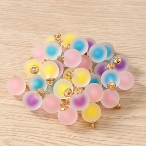 Macro shot of colorful matte resin spherical charms with gold rings for DIY jewelry making