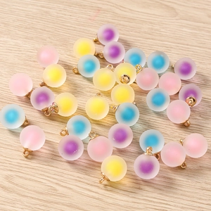 Close-up of frosted glass ball charms in pastel colors with gold metal loops for DIY jewelry