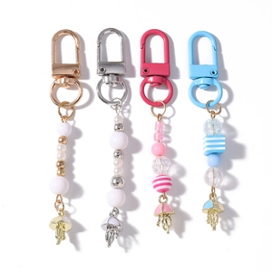 Detail of four colorful jellyfish keychains with beads and tassels on a white background