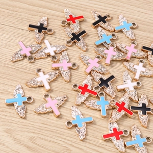 Macro detail of colorful angel wing cross charms with polished gold finish on wood
