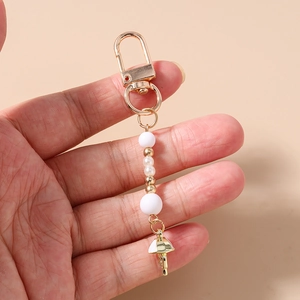 Detail of beaded keychain with matte white pearls and gold jellyfish charm pendant
