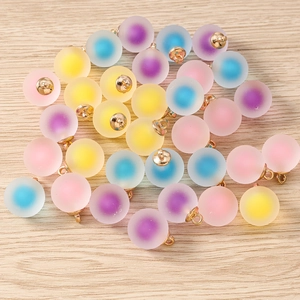 Macro shot of colorful frosted resin ball charms with gold loops on wooden texture
