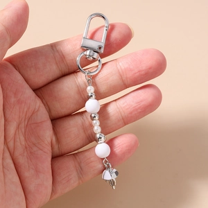 Detail of beaded keychain featuring faux pearls and silver jellyfish tassel charm