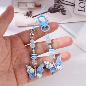 Detailed macro of a blue butterfly beaded phone charm with resin floral accents
