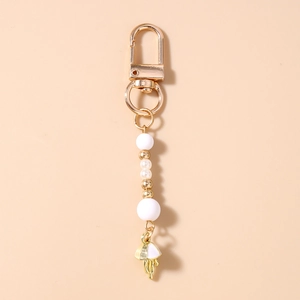 Detail view of a gold lobster clasp keychain featuring white beads and jellyfish pendant
