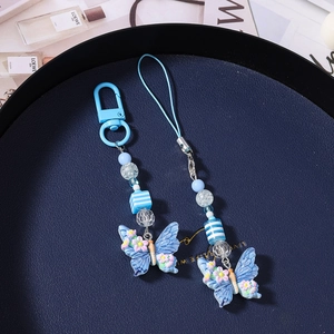 Detailed macro view of blue butterfly phone charms with small floral patterns on a blue tray