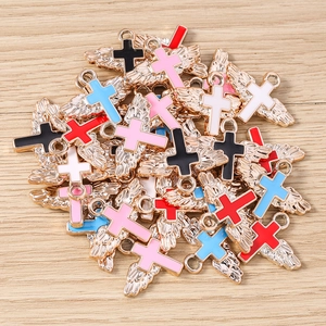 Macro detail of mixed color enamel angel wing cross pendants on wood background