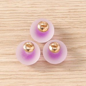 Detail view of purple frosted round ball pendants with gold metal caps for DIY jewelry