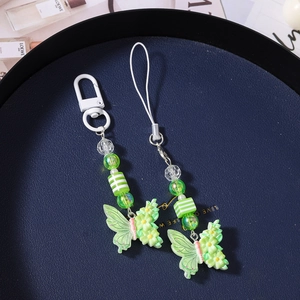 Detail of green resin butterfly charms with floral patterns on a dark blue tray