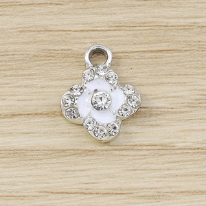 Macro detail of silver clover pendant with white enamel and sparkling crystals