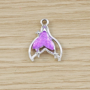 Macro detail of a silver fish tail heart charm with purple enamel and star for DIY jewelry