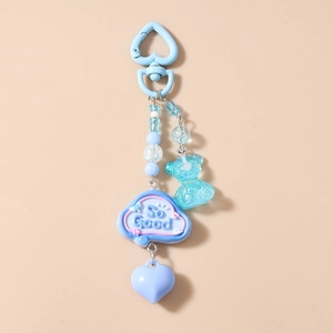 Detail of blue beaded keychain with bear pendant and heart clasp on a plain background