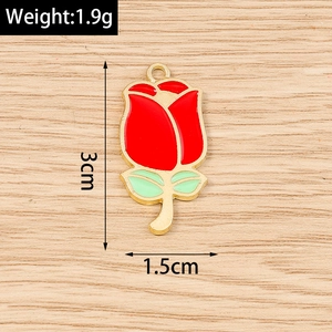 Detail of red flower pendant charm with gold metal edges and green leaves on wood