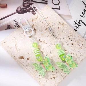 Detail of green resin butterfly charms with pearlescent beads on stone background