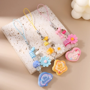 Detailed macro view of colorful daisy beaded phone charms with metal lobster clasps