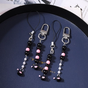 Bijoux de téléphone perlés avec pendentifs arrosoirs noirs et cœurs roses sur un plateau