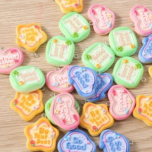 Macro shot of colorful resin candy charms with engraved quotes and floral patterns