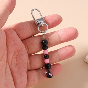 Détail de la dragonne de téléphone perlée avec perles roses et pendentif théière noire
