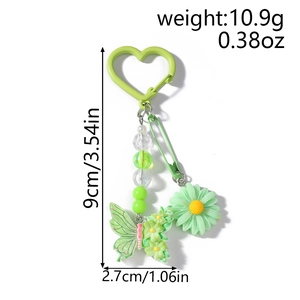 Détail d'un porte-clés vert avec papillon, marguerite, perles et crochet cœur