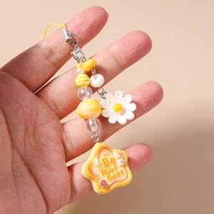 Detail of yellow star phone charm with Be Your Best slogan and white daisy floral bead